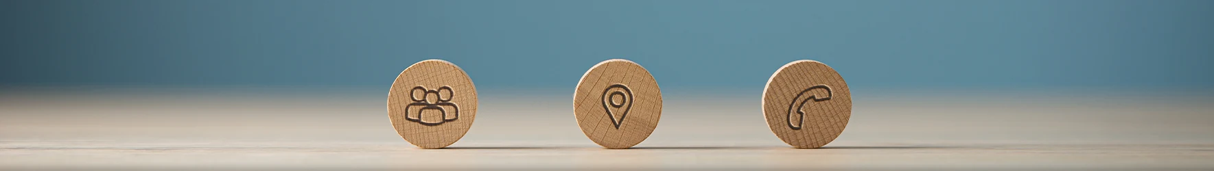 Holzscheiben mit Symbolen für Team, Standort und Telefon